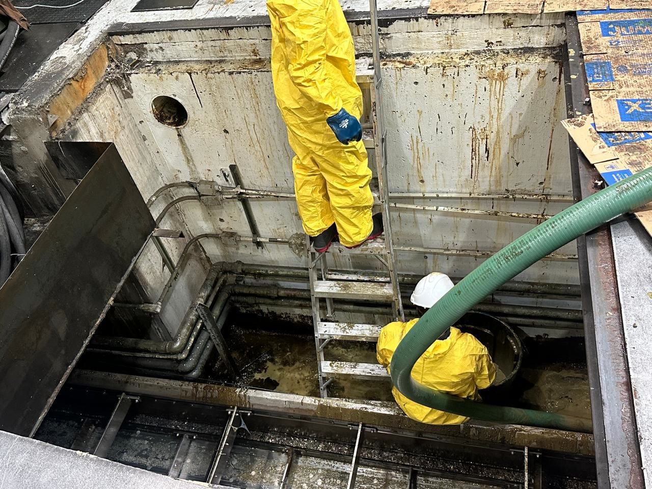Personal de AMJ limpiando una fosa industrial con equipo de protección